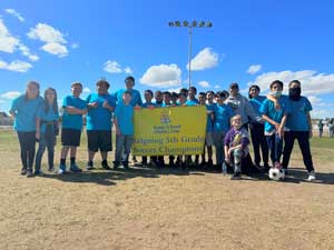 Soccer team behind banner that reads Yuma School District One Reigning 5th Grade Soccer Champions